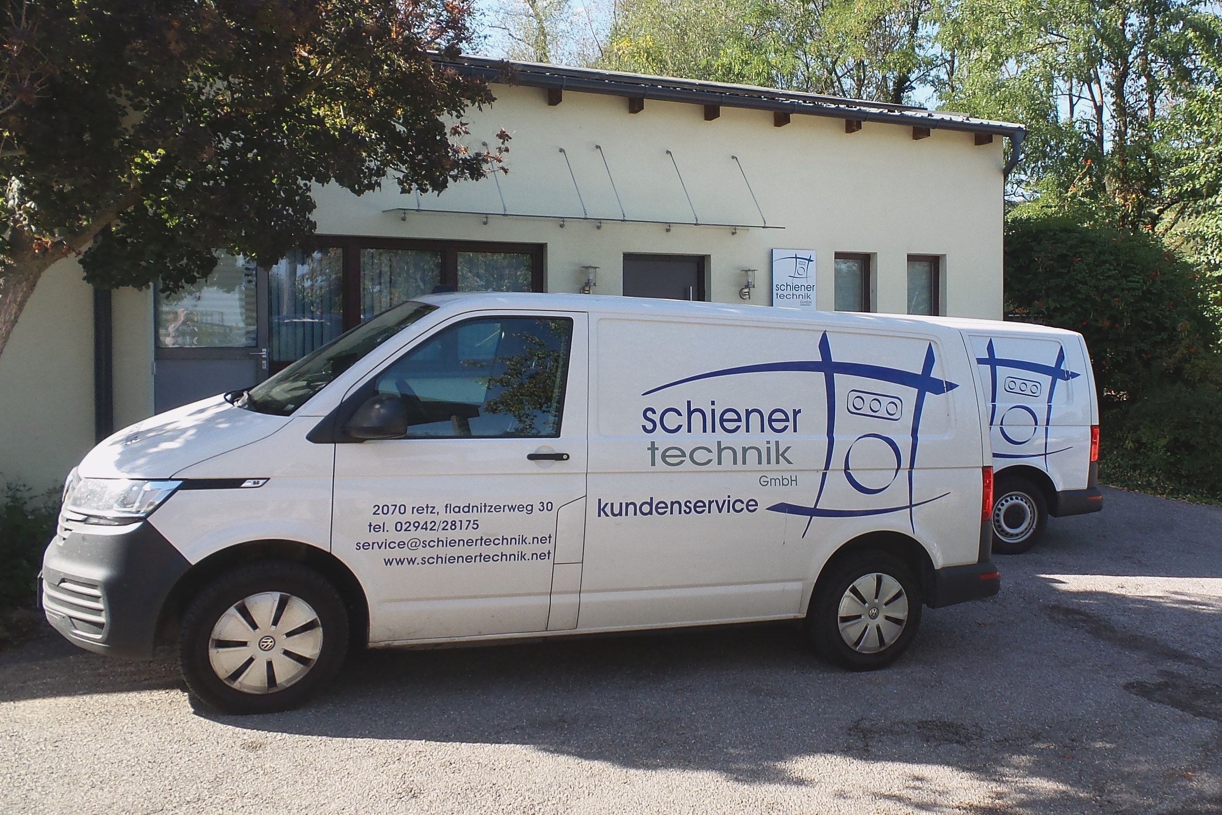 Firmengebäude der schiener technik GmbH in Retz mit Firmenschild, davor zwei beschriftete Servicefahrzeuge